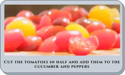 Cut the tomatoes in half and add them to the cucumber and peppers