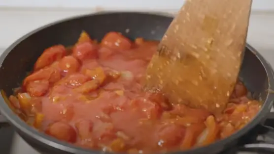 Break the tomatoes with a wooden spoon